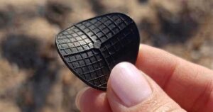 Dettaglio di un dischetto nero di plastica tipo carrier per depuratori ritrovato in spiaggia.