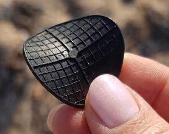 Dettaglio di un dischetto nero di plastica tipo carrier per depuratori ritrovato in spiaggia.