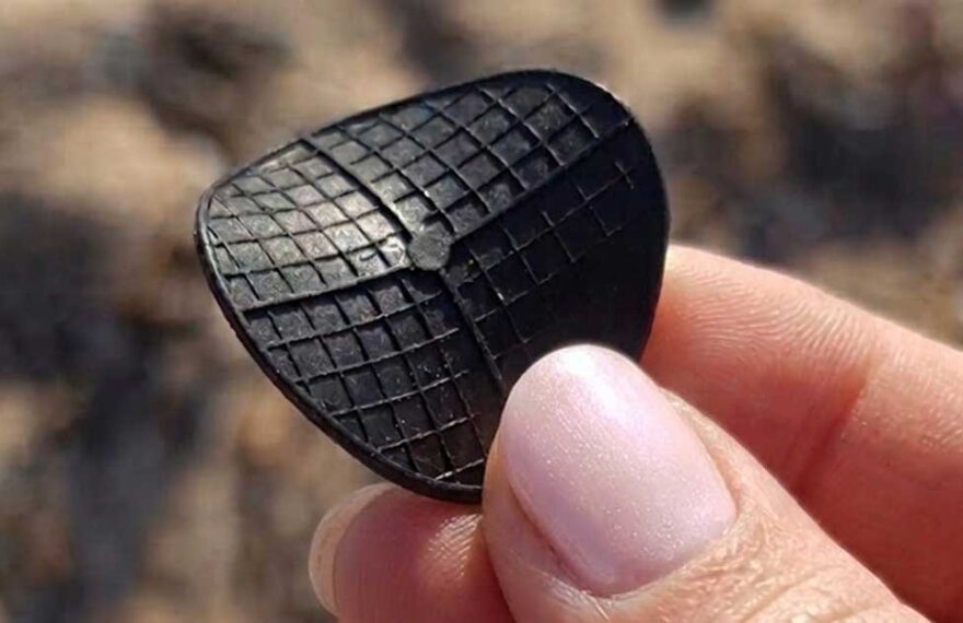 Dettaglio di un dischetto nero di plastica tipo carrier per depuratori ritrovato in spiaggia.