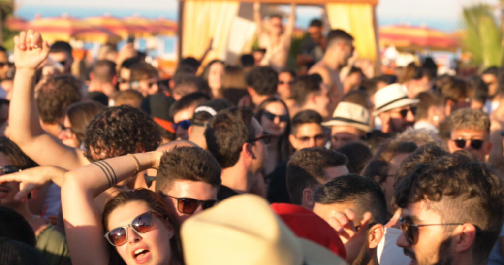 Folla di giovani che balla durante un aperitivo e party in spiaggia a Milano Marittima.