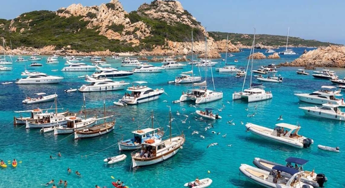 Numerose imbarcazioni da diporto e catamarani ormeggiati nelle acque trasparenti dell'arcipelago di La Maddalena