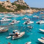 Numerose imbarcazioni da diporto e catamarani ormeggiati nelle acque trasparenti dell'arcipelago di La Maddalena