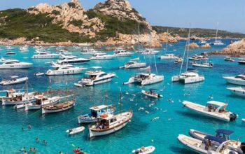 Numerose imbarcazioni da diporto e catamarani ormeggiati nelle acque trasparenti dell'arcipelago di La Maddalena