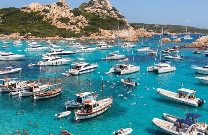 Numerose imbarcazioni da diporto e catamarani ormeggiati nelle acque trasparenti dell'arcipelago di La Maddalena