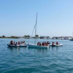Giovani allievi della scuola di vela con giubbotto salvagente seduti a bordo di una barca a vela nel mare di Grado