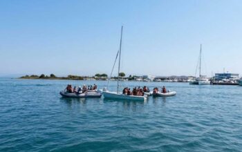 Giovani allievi della scuola di vela con giubbotto salvagente seduti a bordo di una barca a vela nel mare di Grado