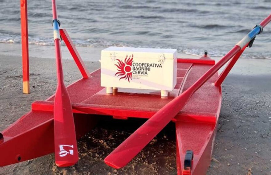 Un moscone di salvataggio rosso della Cooperativa Bagnini Cervia posizionato sulla battigia di fronte al mare.