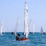 Flotta di imbarcazioni a vela e derive in gara sul mare davanti alla costa durante la Prosecco's Cup