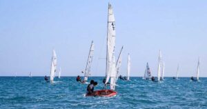 Flotta di imbarcazioni a vela e derive in gara sul mare davanti alla costa durante la Prosecco's Cup