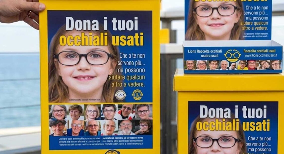 Contenitori gialli della raccolta occhiali usati del Lions Club posizionati presso uno stabilimento balneare.