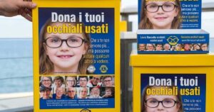 Contenitori gialli della raccolta occhiali usati del Lions Club posizionati presso uno stabilimento balneare.