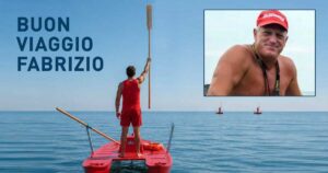 Bagnino su pattino di salvataggio alza un remo verso il cielo in segno di rispetto, con un ritratto di Fabrizio Valente e la scritta "BUON VIAGGIO FABRIZIO".