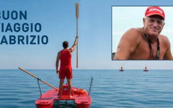 Bagnino su pattino di salvataggio alza un remo verso il cielo in segno di rispetto, con un ritratto di Fabrizio Valente e la scritta "BUON VIAGGIO FABRIZIO".