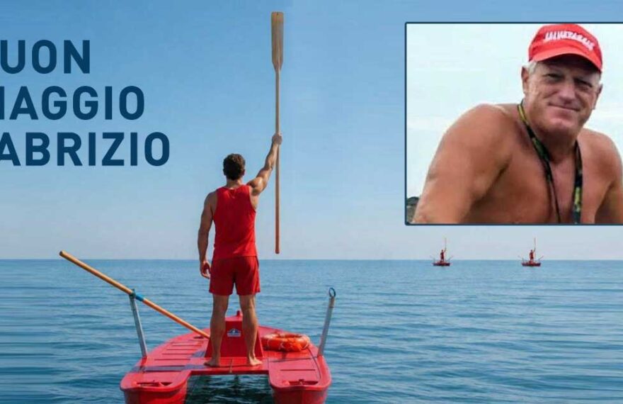 Bagnino su pattino di salvataggio alza un remo verso il cielo in segno di rispetto, con un ritratto di Fabrizio Valente e la scritta "BUON VIAGGIO FABRIZIO".