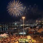 Veduta aerea notturna del piazzale del porto di Termoli affollato per la Sagra del Pesce con spettacolo di fuochi d'artificio