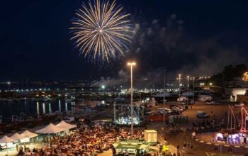 Veduta aerea notturna del piazzale del porto di Termoli affollato per la Sagra del Pesce con spettacolo di fuochi d'artificio