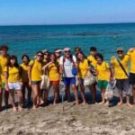 I giovani volontari del progetto Sentinelle del Sinis in maglietta gialla sulla spiaggia di Cabras.