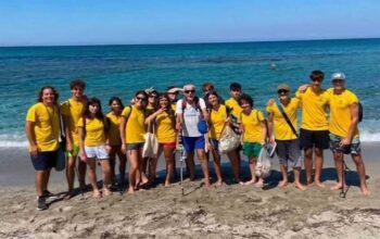 I giovani volontari del progetto Sentinelle del Sinis in maglietta gialla sulla spiaggia di Cabras.
