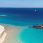 La spiaggia di Su Giudeu a Chia con la sabbia bianca, il mare cristallino e l'omonimo isolotto sullo sfondo.