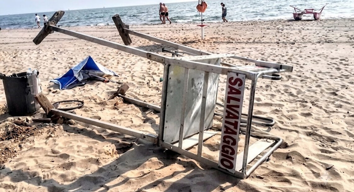 Torretta di salvataggio rovesciata sulla sabbia dopo un atto vandalico in spiaggia.