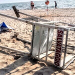 Torretta di salvataggio rovesciata sulla sabbia dopo un atto vandalico in spiaggia.