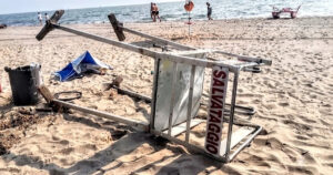 Torretta di salvataggio rovesciata sulla sabbia dopo un atto vandalico in spiaggia.