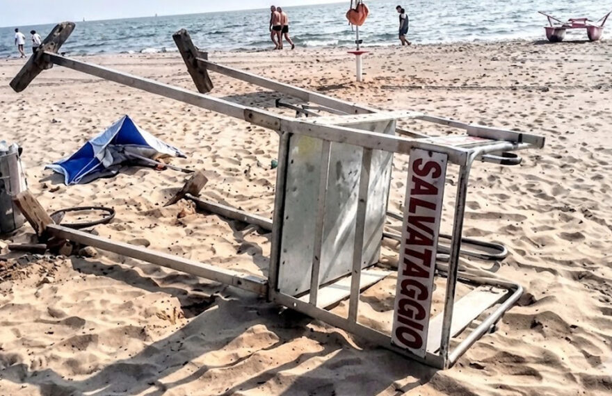 Torretta di salvataggio rovesciata sulla sabbia dopo un atto vandalico in spiaggia.