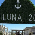 Insegna in verde dello stabilimento balneare Miluna 209 a Cervia con l'ancora e il camminamento d'ingresso.