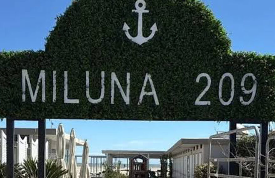 Insegna in verde dello stabilimento balneare Miluna 209 a Cervia con l'ancora e il camminamento d'ingresso.