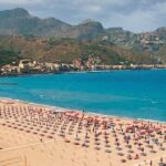 Veduta aerea del litorale e degli stabilimenti balneari di Giardini Naxos con ombrelloni e mare