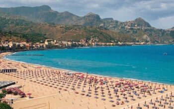 Veduta aerea del litorale e degli stabilimenti balneari di Giardini Naxos con ombrelloni e mare