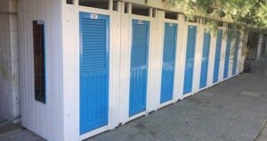 Fila di cabine balneari in legno bianche con porte blu allo stabilimento Bagni Colombo di Spotorno