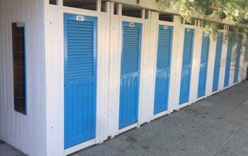 Fila di cabine balneari in legno bianche con porte blu allo stabilimento Bagni Colombo di Spotorno