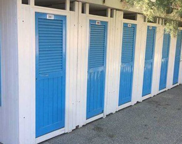 Fila di cabine balneari in legno bianche con porte blu allo stabilimento Bagni Colombo di Spotorno