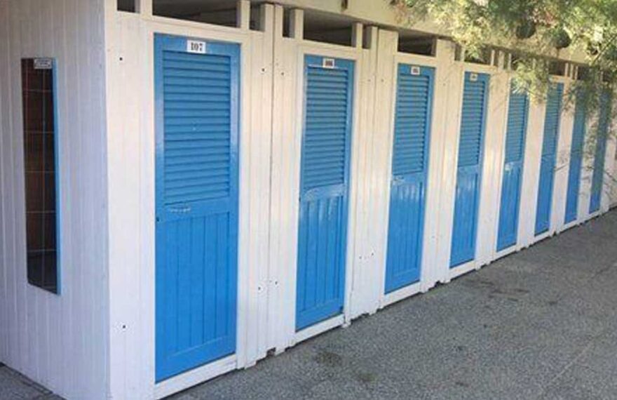 Fila di cabine balneari in legno bianche con porte blu allo stabilimento Bagni Colombo di Spotorno