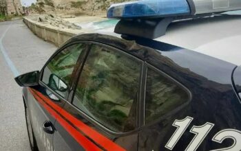 Un'auto dei Carabinieri in pattugliamento lungo la costa del Vibonese, sullo sfondo del promontorio di Tropea.