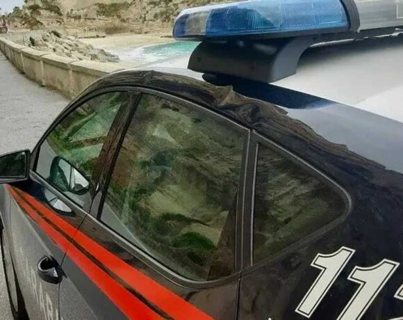 Un'auto dei Carabinieri in pattugliamento lungo la costa del Vibonese, sullo sfondo del promontorio di Tropea.