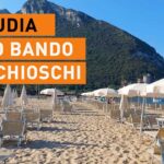 Spiaggia di Sabaudia con lettini, ombrelloni e il promontorio del Circeo sullo sfondo.