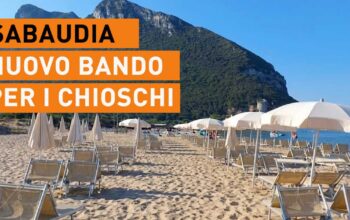 Spiaggia di Sabaudia con lettini, ombrelloni e il promontorio del Circeo sullo sfondo.