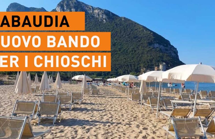 Spiaggia di Sabaudia con lettini, ombrelloni e il promontorio del Circeo sullo sfondo.