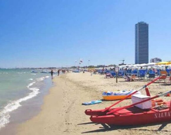 Vista della spiaggia di Cesenatico con pattino di salvataggio rosso in primo piano e il grattacielo sullo sfondo