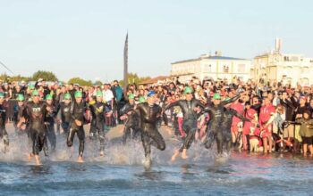 Atleti dell'Ironman in corsa verso il mare per la prova di nuoto sulla spiaggia di Cervia