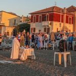 Celebrazione della messa all'alba sulla spiaggia dei Bagni San Pietro a Borgio Verezzi con numerosi fedeli presenti.