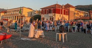 Celebrazione della messa all'alba sulla spiaggia dei Bagni San Pietro a Borgio Verezzi con numerosi fedeli presenti.
