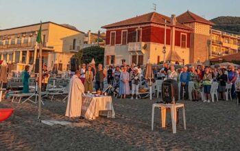 Celebrazione della messa all'alba sulla spiaggia dei Bagni San Pietro a Borgio Verezzi con numerosi fedeli presenti.