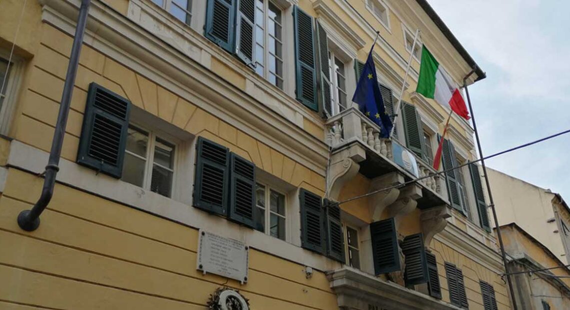 Facciata del municipio di Finale Ligure con bandiere istituzionali su balcone