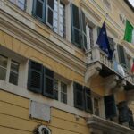 Facciata del municipio di Finale Ligure con bandiere istituzionali su balcone
