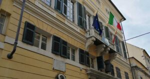 Facciata del municipio di Finale Ligure con bandiere istituzionali su balcone