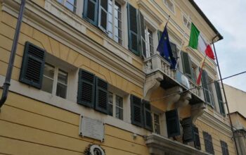 Facciata del municipio di Finale Ligure con bandiere istituzionali su balcone