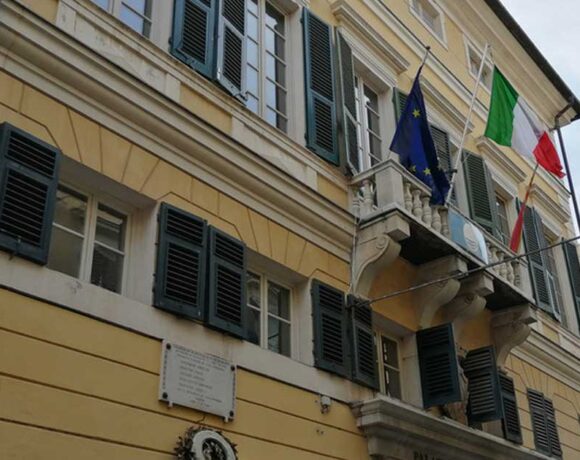 Facciata del municipio di Finale Ligure con bandiere istituzionali su balcone